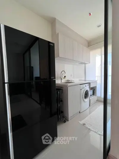 Modern kitchen with sleek black fridge and washing machine in bright apartment