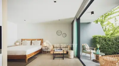 Luxurious bedroom with large glass doors opening to a lush garden view, featuring modern decor and cozy seating.