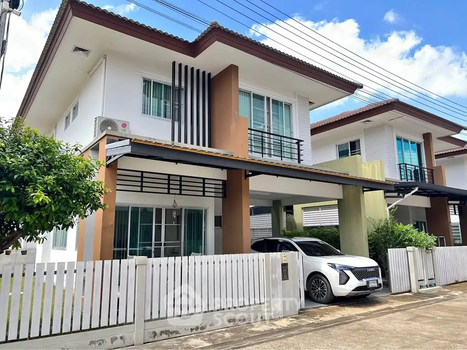 Modern two-story house with carport and white picket fence in a suburban neighborhood.