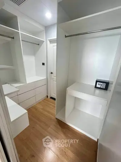 Spacious walk-in closet with modern white shelving and secure safe, perfect for organized storage.