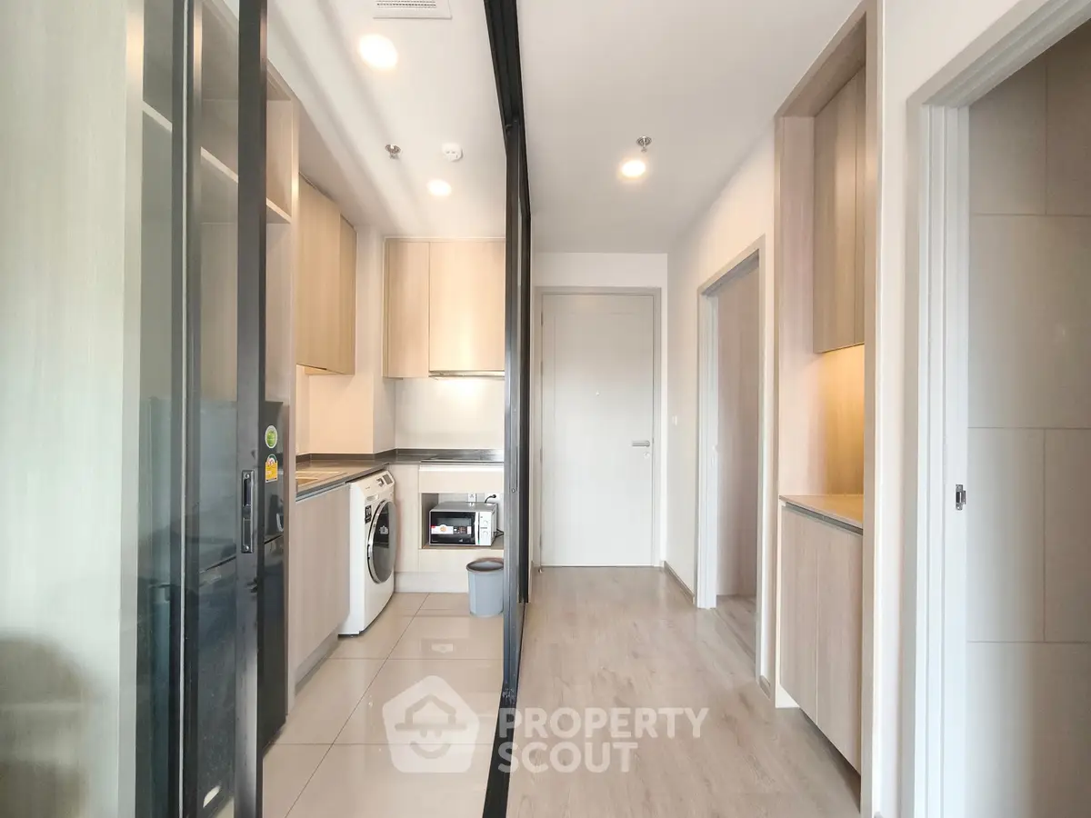 Modern kitchen with sleek appliances and wooden cabinetry in a bright apartment.
