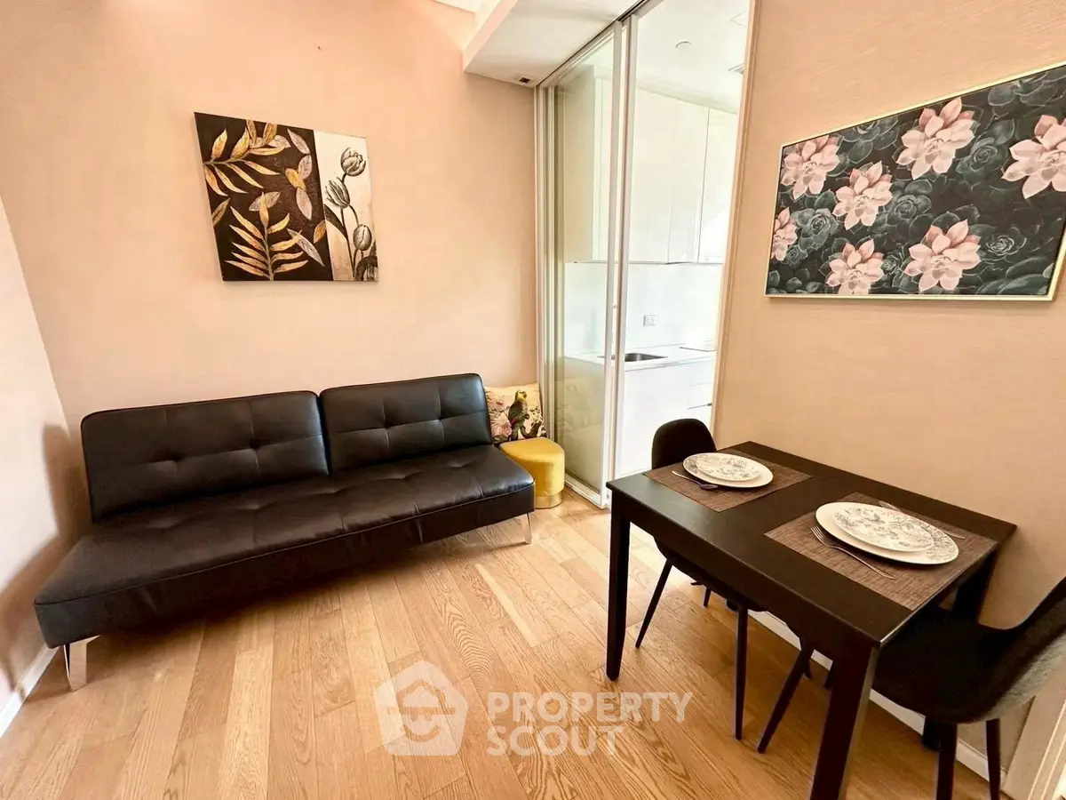 Chic living room with modern sofa and dining area, featuring elegant floral artwork and sleek wooden flooring.