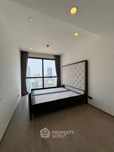 Modern bedroom with large window offering stunning city views and elegant decor.