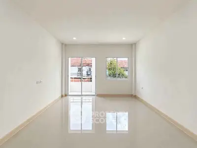 Spacious empty room with glossy tiled floor and large windows offering natural light.