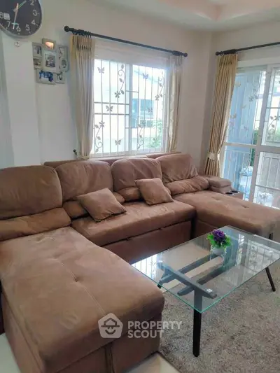 Spacious living room with plush sectional sofa and glass coffee table, perfect for relaxation and entertaining.