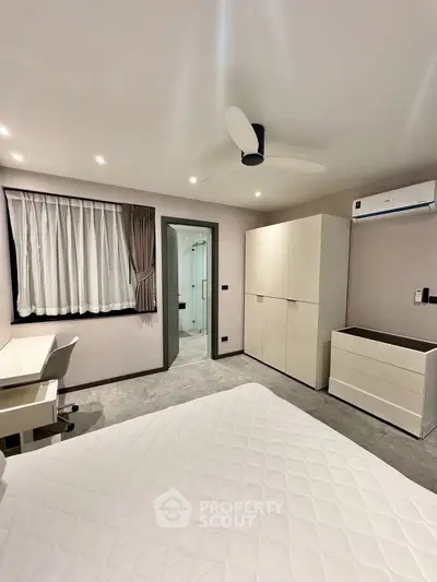 Modern bedroom with sleek furniture and ensuite bathroom in a stylish apartment.