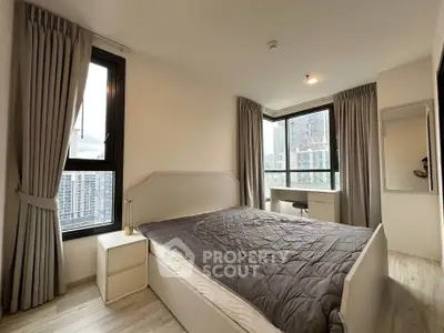 Modern bedroom with large windows and city view, featuring elegant curtains and stylish furniture.