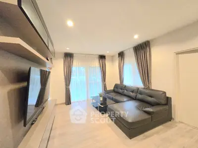 Modern living room with sleek black sofa and large TV, featuring elegant curtains and stylish decor.