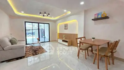 Modern living room with elegant lighting and dining area, featuring sleek furniture and large windows.