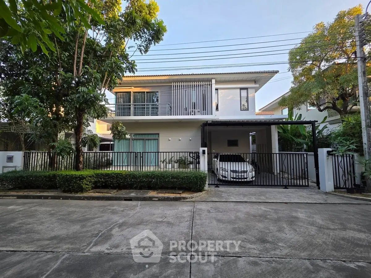 Modern two-story house with carport and lush greenery in a serene neighborhood.