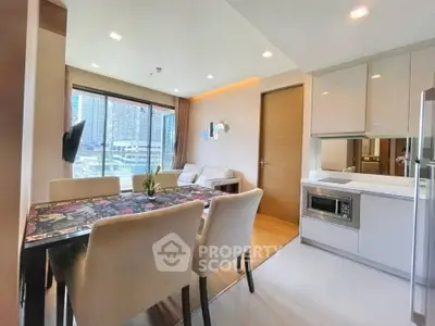 Modern open-layout living and dining area with city view, featuring sleek furniture and built-in kitchen appliances.