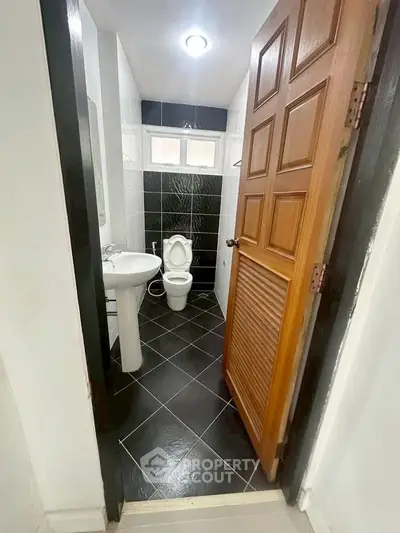 Compact bathroom with modern black and white tiles and wooden door