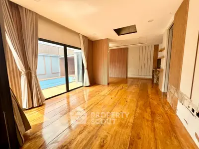 Spacious living room with wooden flooring and poolside view