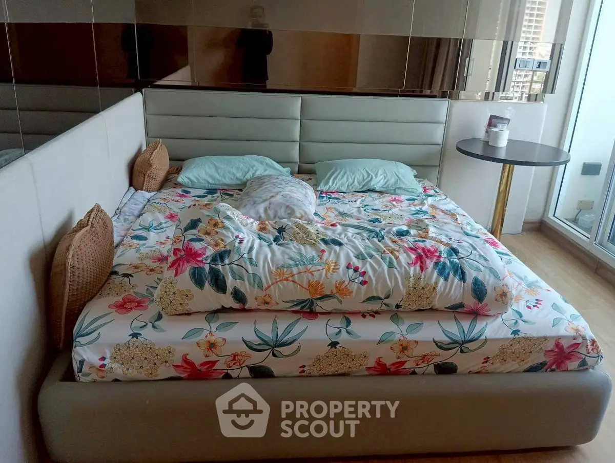 Spacious bedroom with floral bedding and balcony access in modern apartment.