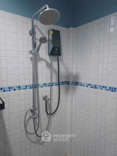Modern bathroom with sleek showerhead and white tiled walls featuring blue accents.