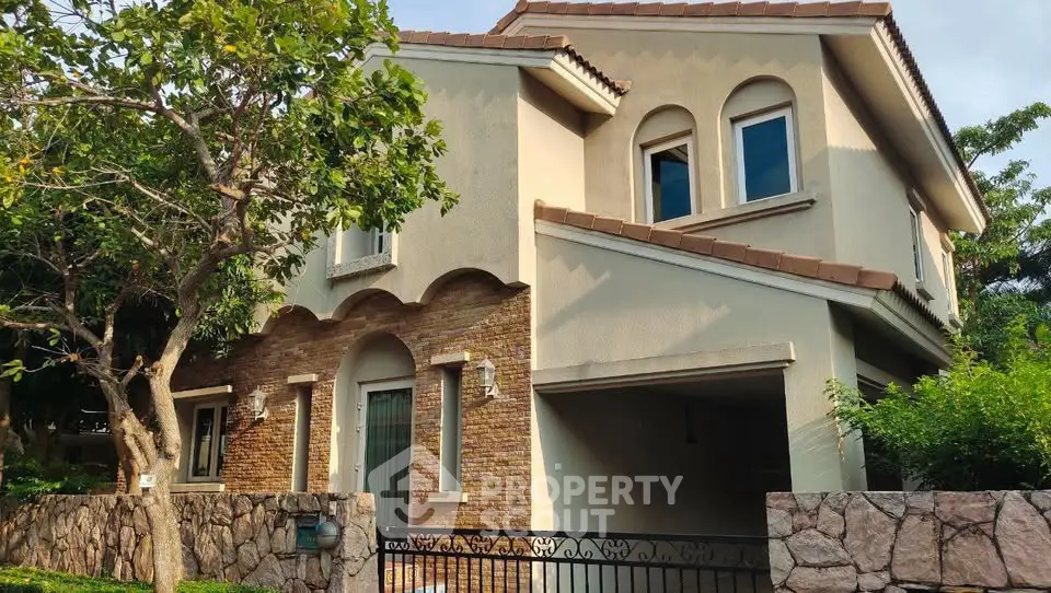 Charming two-story house with brick accents and lush greenery, perfect for family living.