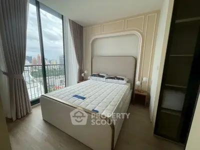 Modern bedroom with large window and city view, featuring elegant decor and natural light.