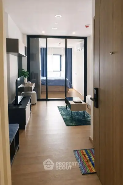 Modern apartment interior with open living room and bedroom view, featuring stylish decor and natural light.