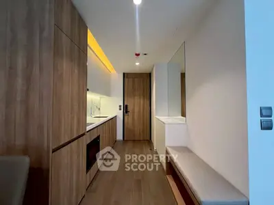 Modern kitchen with sleek wooden cabinets and built-in appliances in a compact layout.