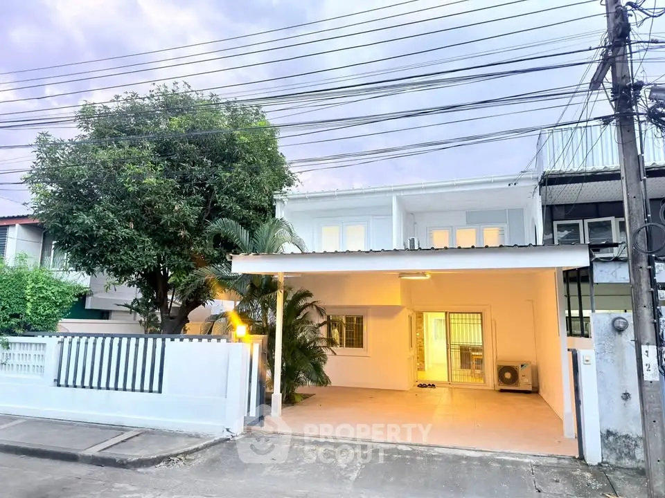 Charming two-story townhouse with carport and lush greenery in a serene neighborhood.