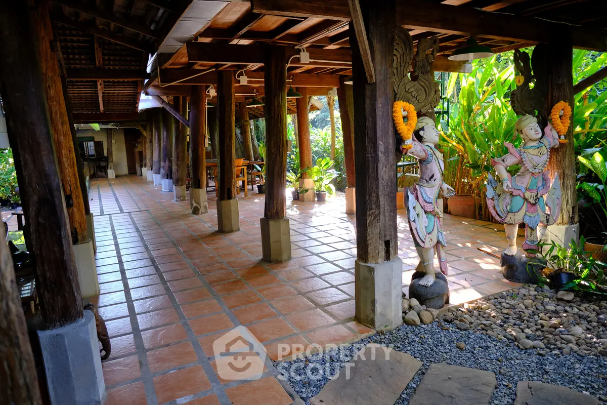 Charming tropical villa entrance with traditional wooden pillars and lush garden view.