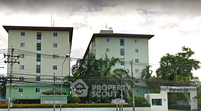 Modern apartment building exterior with lush greenery and secure entrance.