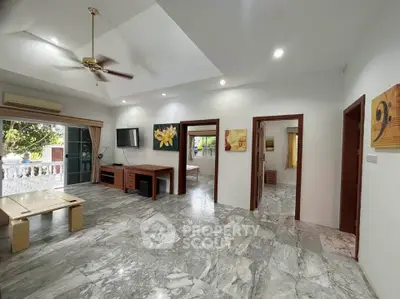 Spacious living room with marble flooring and modern decor, featuring a ceiling fan and large windows.