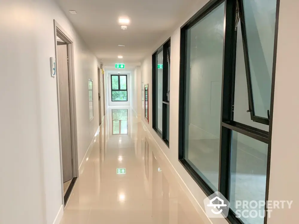 Modern apartment hallway with glossy floors and large windows