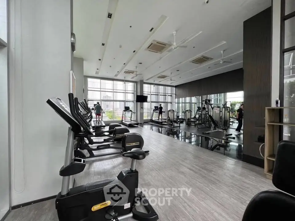 Spacious modern gym with state-of-the-art equipment and large windows for natural light.