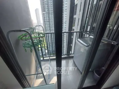 Compact balcony with city view, featuring washing machine and drying rack, ideal for urban living.