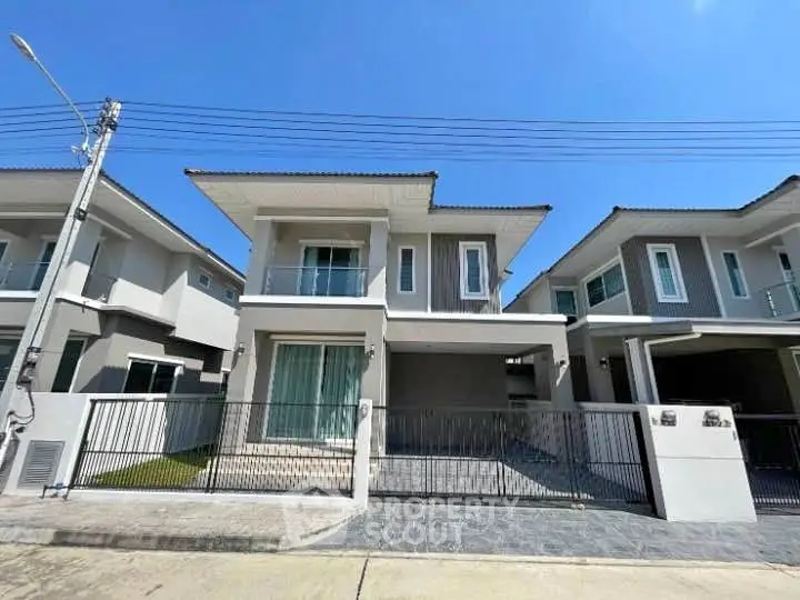 Modern two-story house with sleek design and spacious driveway in a suburban neighborhood.