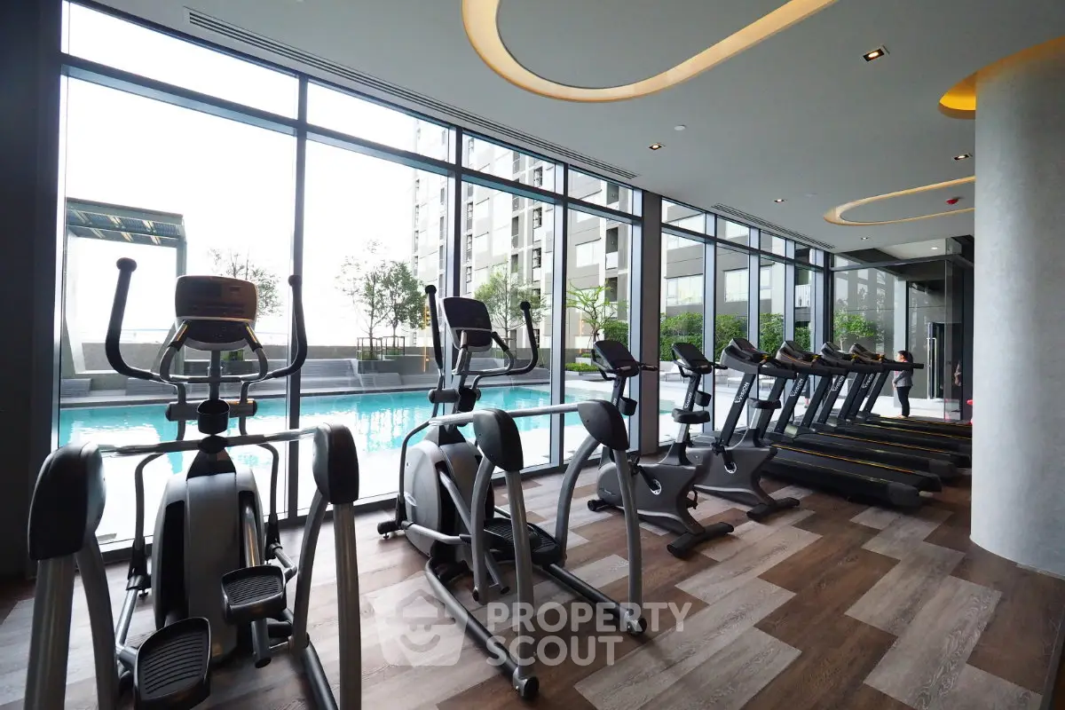 Modern gym with pool view in luxury apartment complex