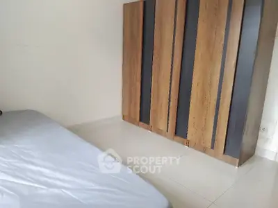 Minimalist bedroom with sleek wardrobe and simple bed setup.