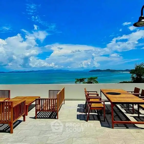 Stunning rooftop terrace with panoramic ocean views and elegant wooden furniture.