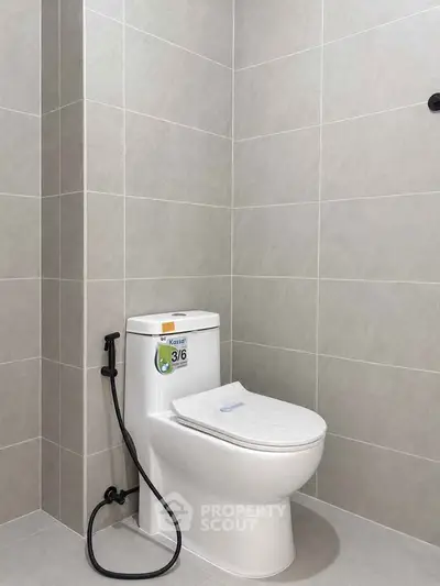 Modern bathroom with sleek tiled walls and a clean toilet setup.
