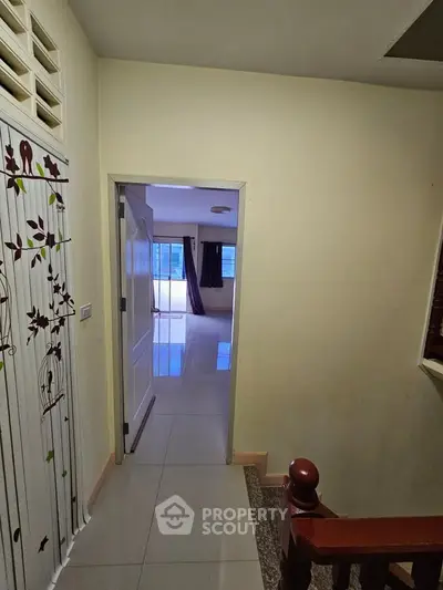 Spacious hallway leading to a bright living room with large windows and modern flooring.