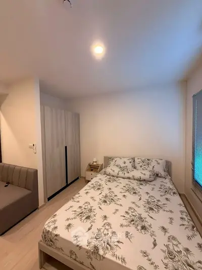 Cozy bedroom with floral bedding and modern wardrobe in a stylish apartment.