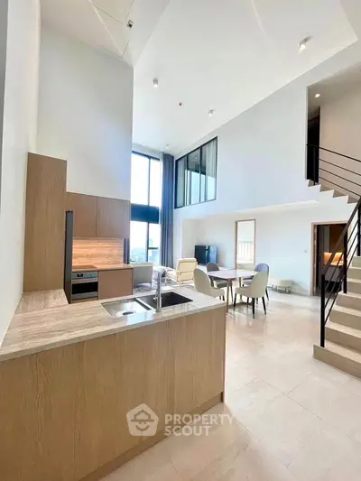 Spacious modern living room with high ceilings and open kitchen layout in luxury apartment.