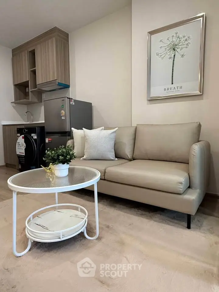 Modern living room with stylish sofa, compact kitchen, and chic decor in a cozy apartment setting.