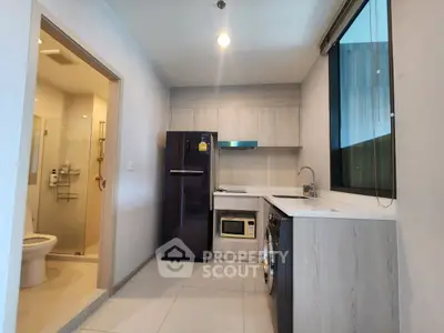 Modern kitchen with sleek appliances and adjacent bathroom in a stylish apartment.