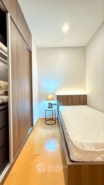 Cozy minimalist bedroom with wooden flooring and built-in wardrobe, perfect for modern living.