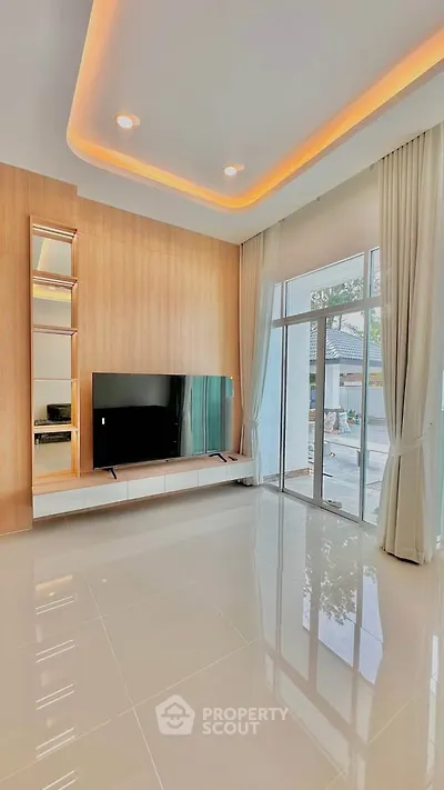 Modern living room with sleek TV setup and large windows offering natural light.