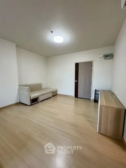 Spacious minimalist living room with wooden flooring and modern furniture.