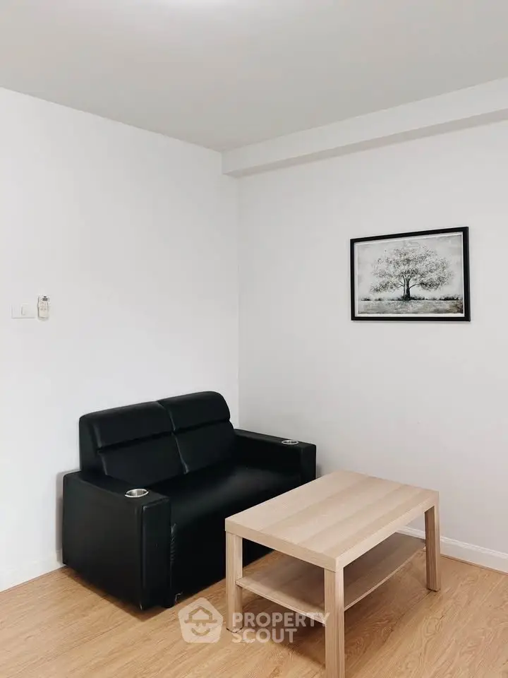 Modern minimalist living room with black leather sofa and wooden coffee table.
