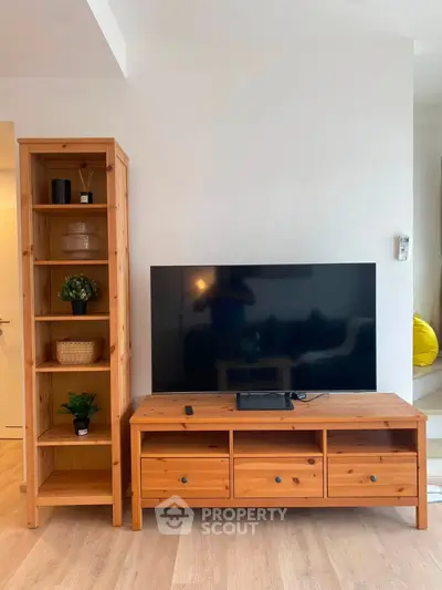 Modern living room with wooden TV stand and shelving unit, showcasing minimalist decor and sleek design.