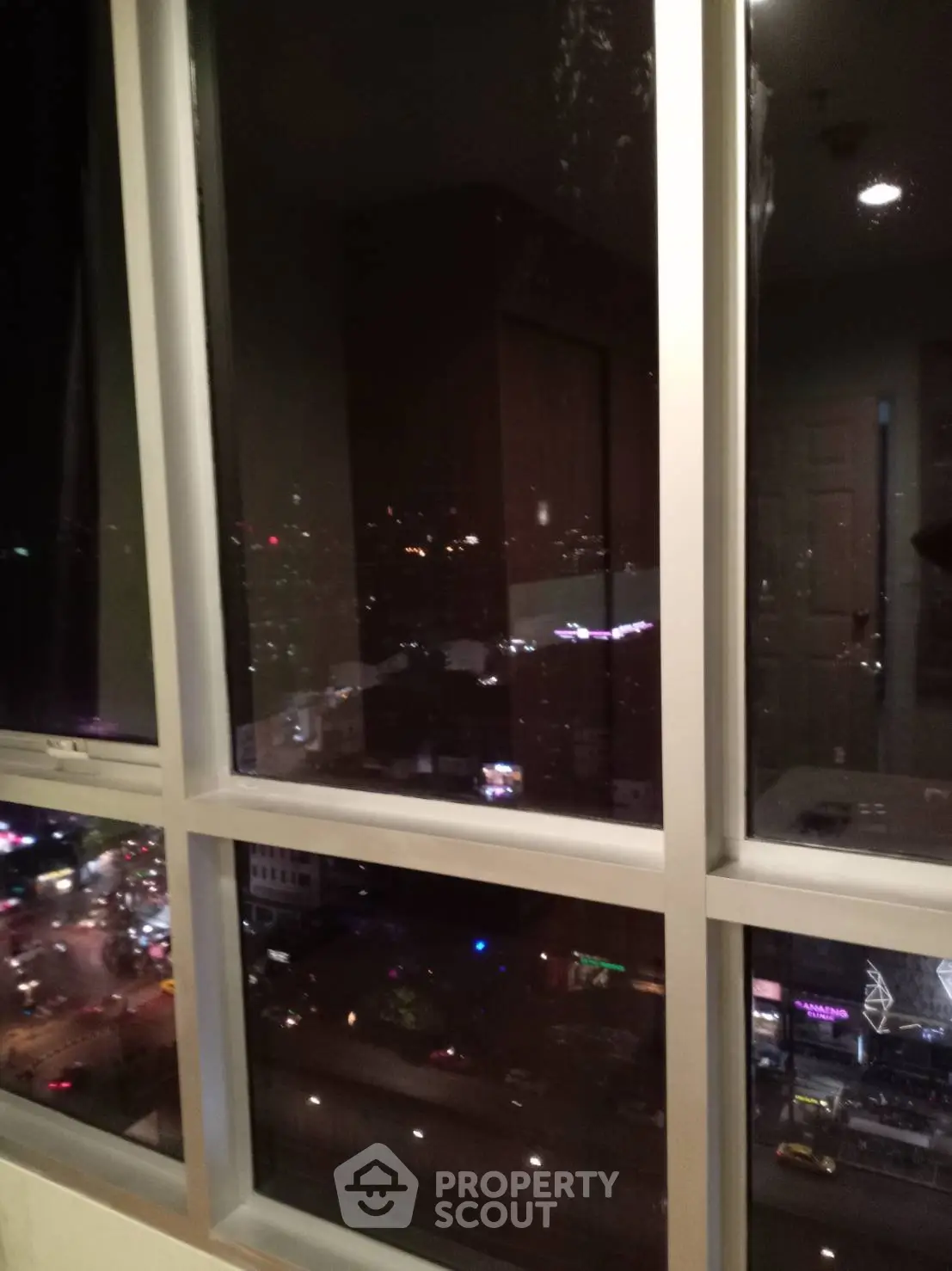 Stunning city view from high-rise apartment window at night, showcasing vibrant urban lights.