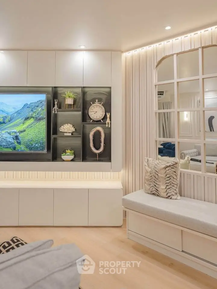 Modern living room with stylish decor and built-in shelving, featuring a cozy seating area and elegant lighting.