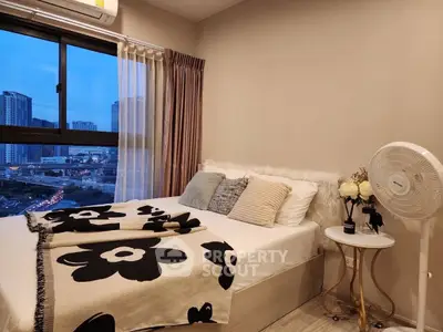 Cozy bedroom with city view, featuring stylish decor and large window for natural light.