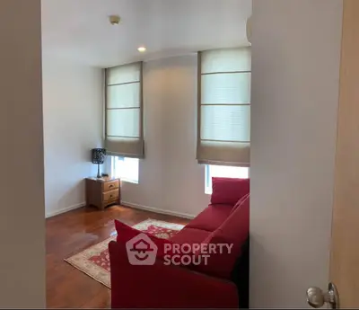 Cozy living room with red sofa and natural light, perfect for relaxation.