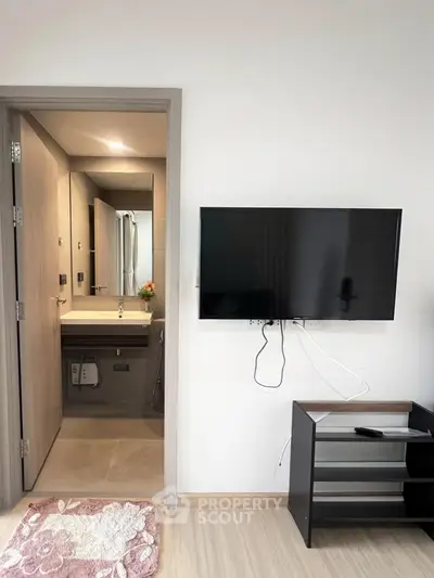 Modern apartment interior with wall-mounted TV and bathroom view, showcasing sleek design and functionality.